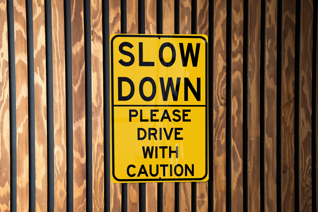 a yellow slow down sign on a wooden wall
