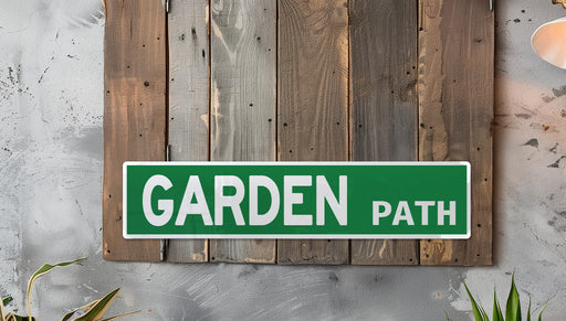 a green garden path sign mounted to a wooden wall