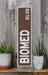 a brown and white sign sitting on top of a wooden shelf