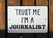 a white sign that says trust me i'm a journalist