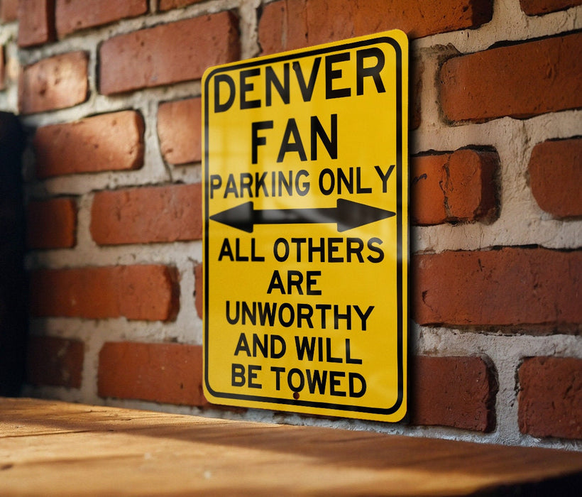 a yellow sign on a brick wall that says denver fan parking only all others are