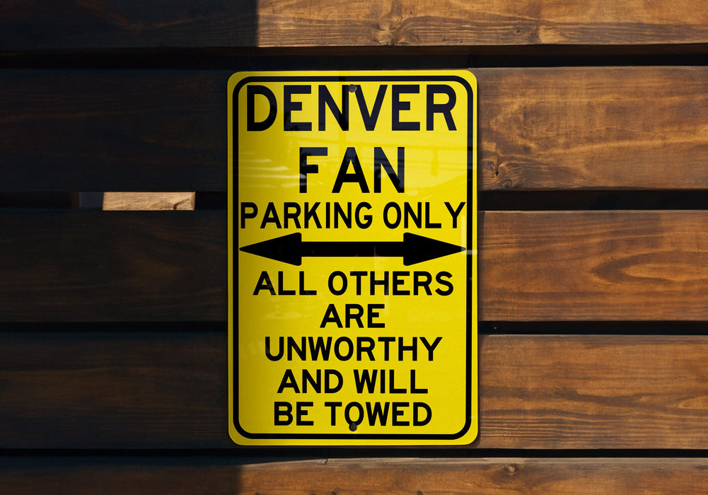 a yellow sign on a wooden wall that says denver fan parking only all others are