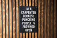 a sign on a wooden wall that says i'm a carpenter because punching people