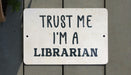 a white sign that says trust me i'm a librarian