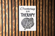 a sign on a wooden wall that says crocheting is my therapy