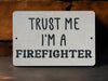 a white sign that says trust me i'm a firefighter