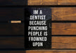 a sign on a wooden bench that says i'm a dentist because punching people
