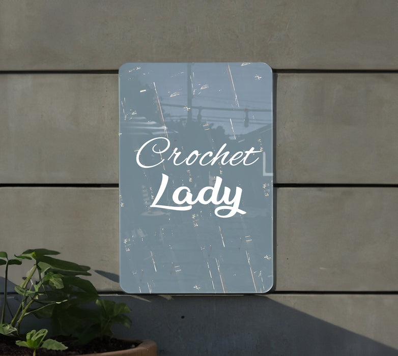 a sign that reads crochet lady next to a potted plant