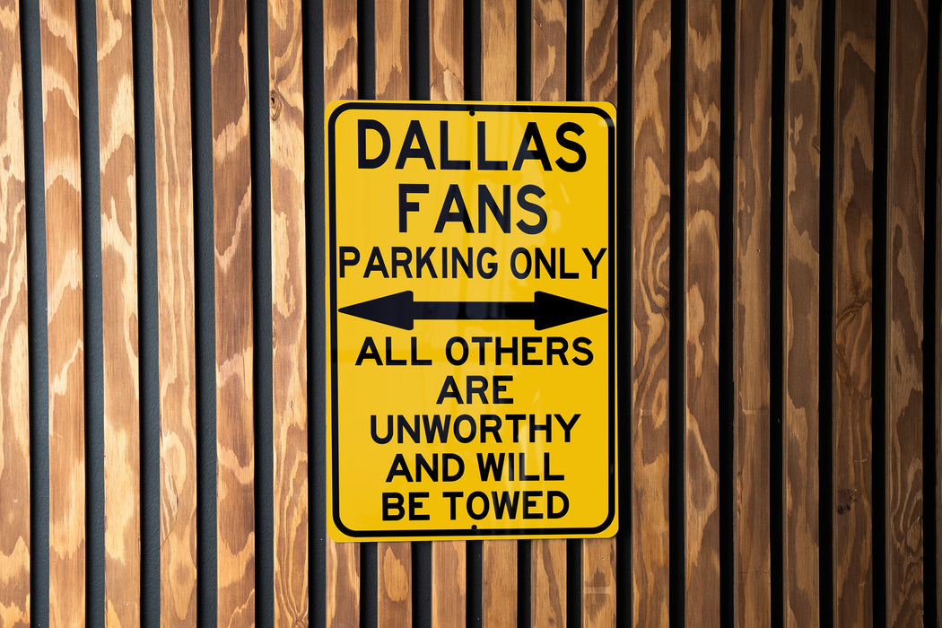 a yellow street sign on a wooden fence