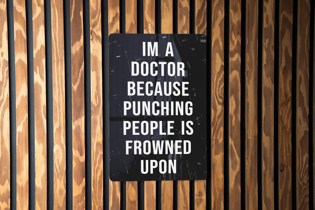 a sign on a wooden wall that says i'm a doctor because punching people