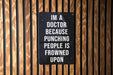 a sign on a wooden wall that says i'm a doctor because punching people
