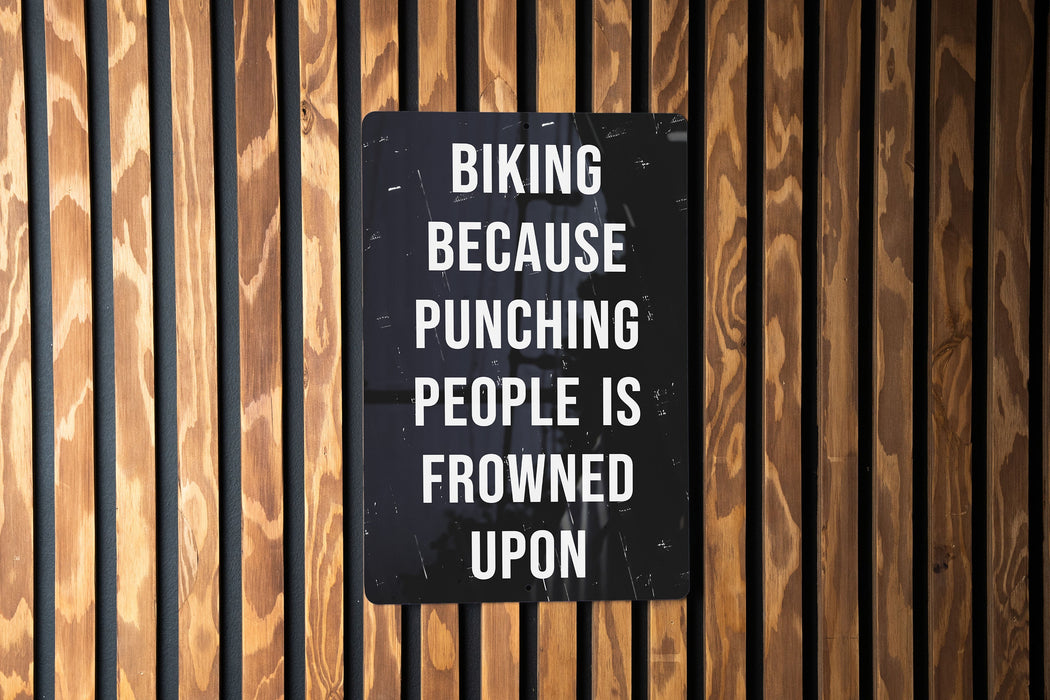a sign on a wooden wall that says biking because punching people is frowned upon