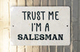 a white sign that says trust me i'm a salesman