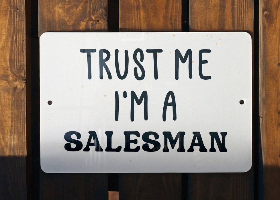 a white sign that says trust me i'm a salesman