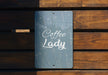 a sign that reads coffee lady on a wooden bench