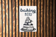 a sign on a wooden wall that says baking nerd