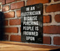 a sign on a brick wall that says i'm an electrician because punching