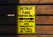 a yellow sign on a wooden wall that says detroit fans parking only all others are