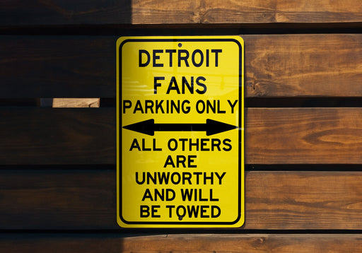a yellow sign on a wooden wall that says detroit fans parking only all others are
