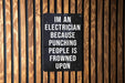 a sign on a wooden wall that says i'm an electrician because punching