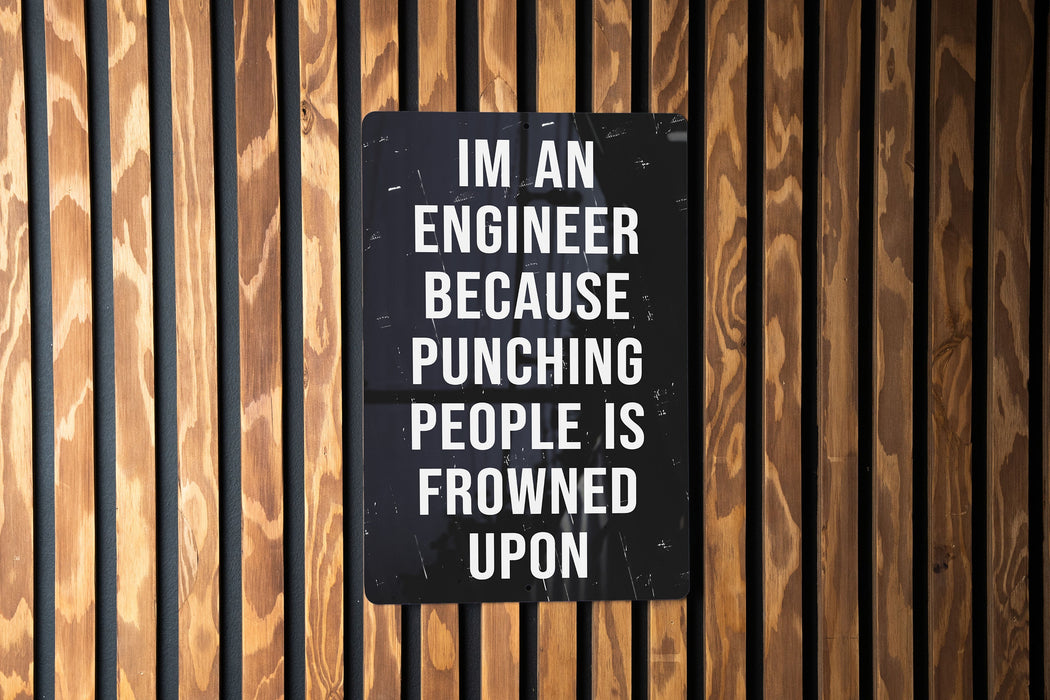 a sign on a wooden wall that says i'm an engineer because punching people