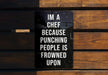a sign on a wooden bench that says i'm a chef because punching people