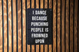 a sign on a wooden wall that says i dance because punching people is frowned