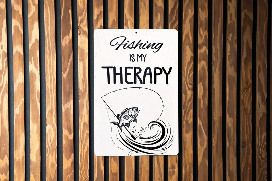 a sign on a wooden wall that says fishing is my therapy