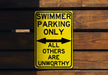a yellow swimming only sign hanging on a wooden wall