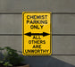 a yellow and black sign that says, chemist parking only all others are un