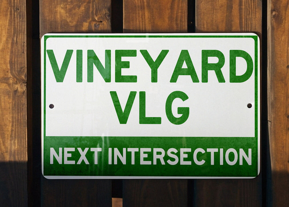a green and white sign that says vineyard vlg next intersection