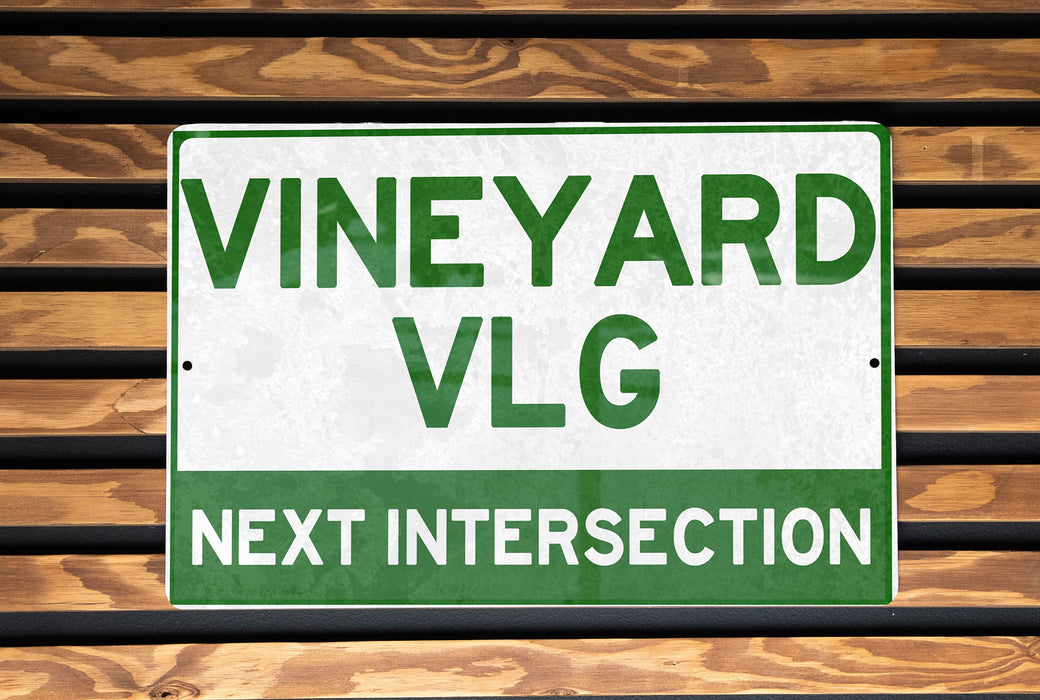 a green and white sign that reads vineyard vlg next intersection