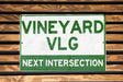 a green and white sign that reads vineyard vlg next intersection