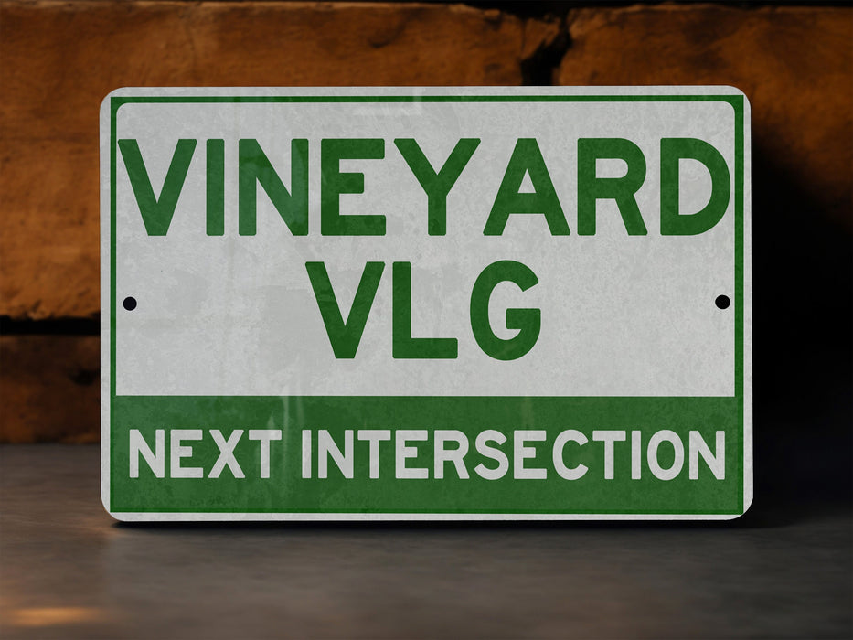 a green and white sign that says vineyard vlg next intersection