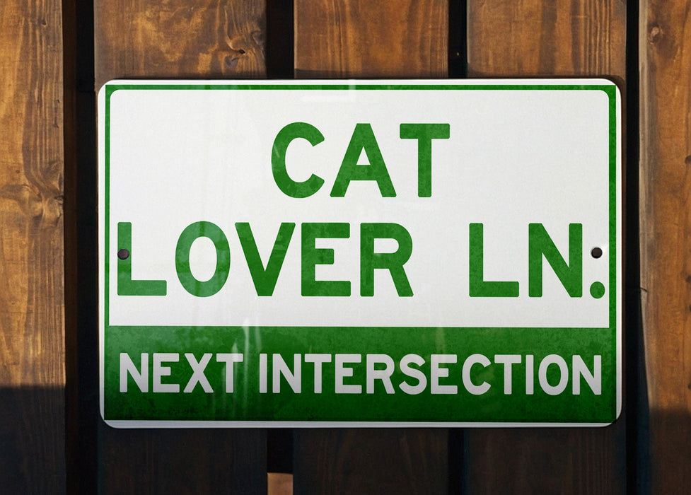 a green and white sign that says cat lover ln next intersection