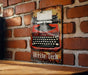 a red and black typewriter on a brick wall