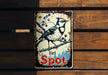 a bird sitting on top of a sign on a wooden wall