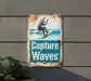 a rusted sign on the side of a building that says capture waves