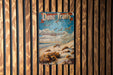a poster of dune trails hangs on a wooden wall
