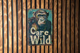 a sign on a wooden wall that says care wild