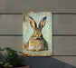 a metal sign with a picture of a rabbit on it
