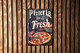 a pizza sign hanging on a wooden wall