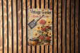 a vintage garden sign hanging on a wooden wall