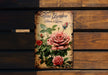 a book with roses painted on it sitting on a bench