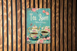 a tea room sign hanging on a wooden wall