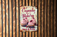 a sign on a wooden wall advertising cupcakes