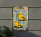 a yellow bird sitting on top of a cage next to a plant