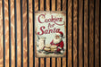 a sign on a wooden wall that says cookies for santa