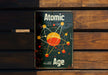 a sign on a wooden bench that says atomic age