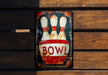 a bowling pin sign on a wooden wall